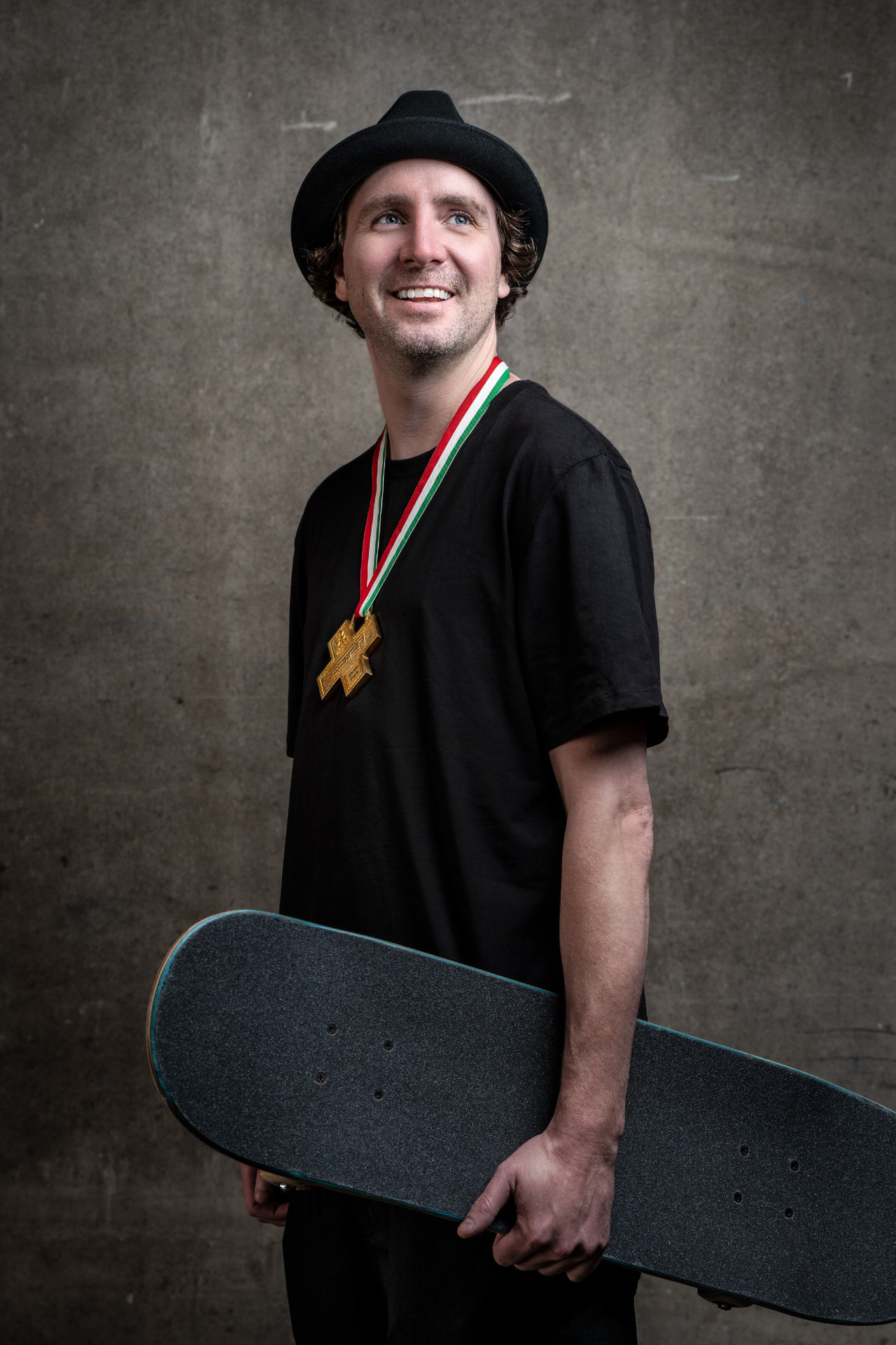 Greg Lutzka wearing an X Games gold medal and holding his skateboard